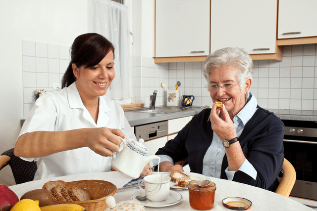 Caregiver serving breakfast to female client